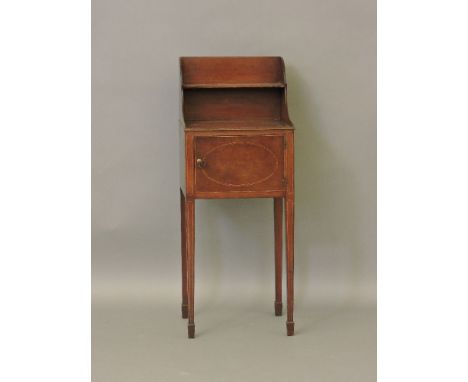 A bedside cupboard, with single inlaid door,  below shelf and shaped top, above four tapered legs