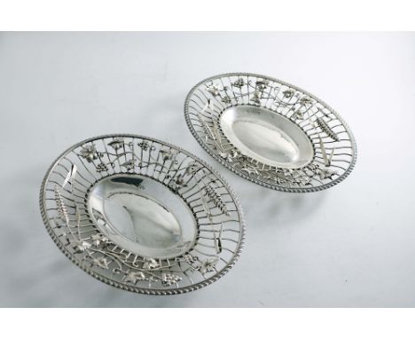 A PAIR OF LATE VICTORIAN PIERCED OVAL DISHES with wirework sides and gadrooned rims, decorated with applied vine leaves &amp;