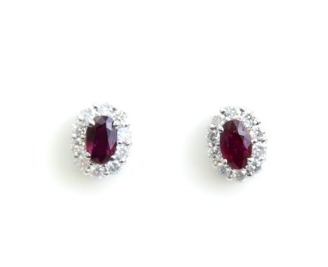 A PAIR OF RUBY AND DIAMOND STUD EARRINGS Featuring two oval rubies accented with round brilliant cut diamonds in a halo setti