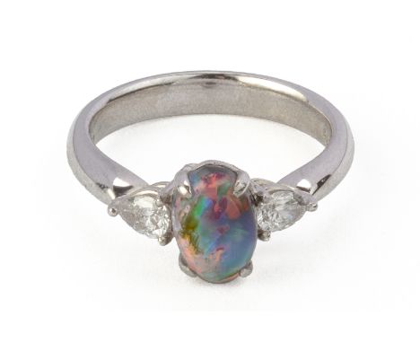 A BlACK OPAL AND DIAMOND THREE STONE RING
Featuring a black opal cabochon weighing approximately 2.76 cts (marked), flanked b