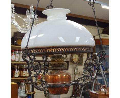 A cast-iron framed copper hanging oil lamp with milk-glass shade 