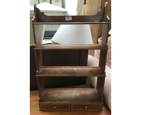 A small wall hanging spice rack, shelves over two drawers 
