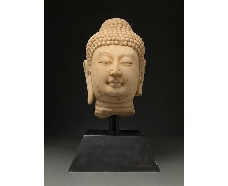 Ca. 1500-1644 AD. Late Ming Dynasty. Cream stone head of a female Guanyin with coiffured hair including a prominent topknot, 