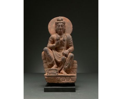 100-300 AD. Gandharan. Schist figure of a bodhisattva, backed by a halo, who sits, gazing serenely into the distance. He is d