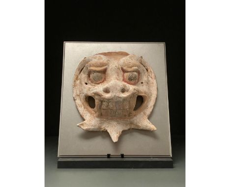 Ca. 206 BC - 220 AD. Han dynasty. A ceramic dragon's head taking a rondel form, with high relief modelling of the brow ridge,