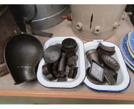 Two enamel dishes containing various tin moulds 