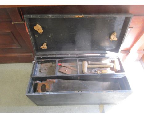 An antique wooden tool box containing various antique tools to include saws and others 