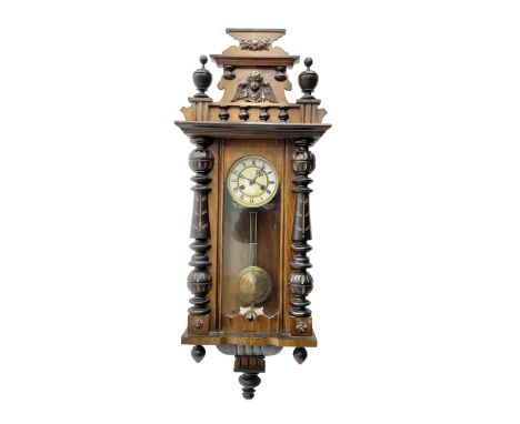 German - late 19th century mahogany and ebonised 8-day wall clock, with a shaped pediment, applied carvings and finials, full