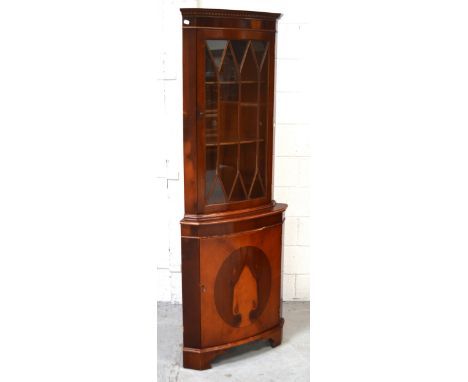 A reproduction mahogany inlaid corner unit, carved frieze over astragal glazed door with two interior shelves above inlaid cu