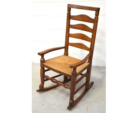A country-style oak ladder back rush-seated rocking chair.