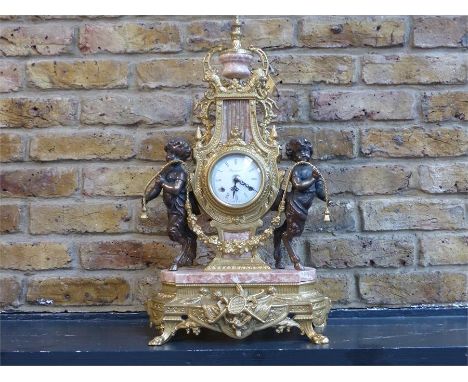 An Italian, 20th century, gilt metal and pink marble mantle clock and garniture set, composed of an ornate clock with white e