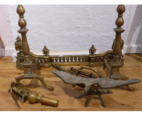 A quantity of antique brass-ware to include a pair of fire dogs, an elaborate cast fire fender with classical urns detailing,