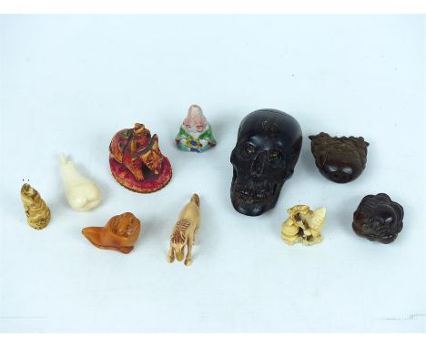 A collection of Japanese carved ivory netsuke, together with other carved items, including a skull.