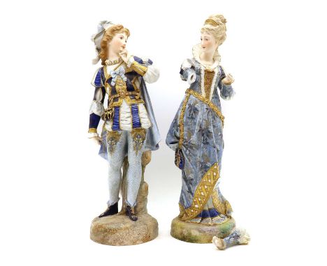 A near pair of porcelain figures, 20th century, part bisque, modelled as a lady and gentleman in traditional costume, raised 