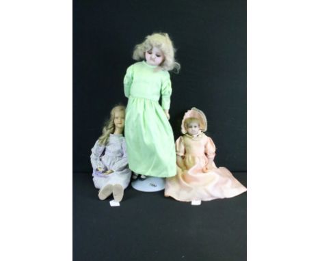 Three late 19th / early 20th century wax headed dolls to include a doll in a green dress (crack to back of head), with glass 