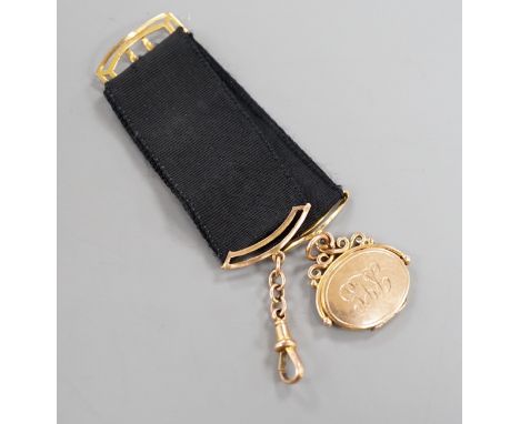 A Victorian yellow metal oval locket fob, hung from a yellow metal mounted black suspension sash, with later engraved date an