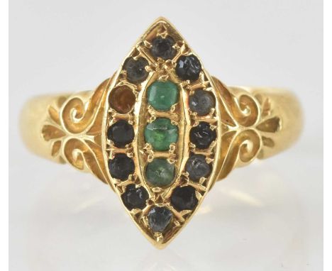 An 18ct gold Art Deco shaped gem set ring, with three central green stones and an outer border of red stones (one missing), s