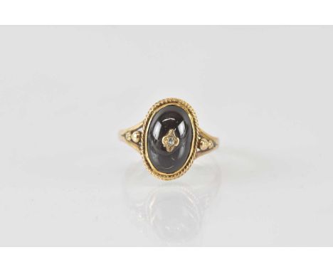 A 9ct gold mourning ring, with tiny diamond to the centre of a red cabochon bezel set stone, with split shoulders, size N, ap