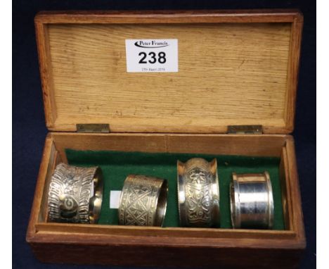 Single silver engine turned napkin ring and three white metal napkin rings in oak box. (B.P. 24% incl. VAT)