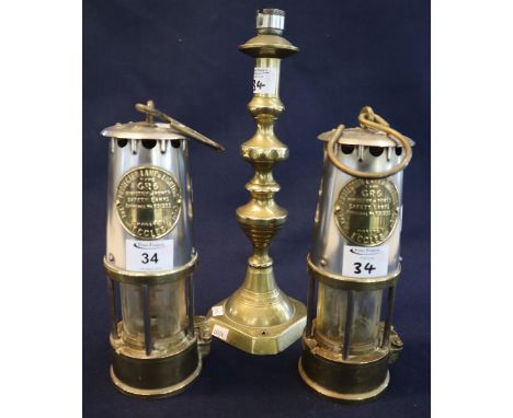 Two Protector Lamp and Lighting Company Ltd brass miner's safety lamps. Together with a large brass candlestick converted as 