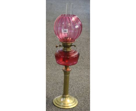 Early 20th Century brass double burner oil lamp with red glass reservoir and brass pedestal base, cranberry glass shade and c