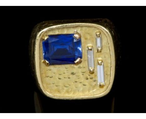 1970s yellow metal and gem set ring with a large square textured gold bezel with step cut blue stone and three baguette cut d