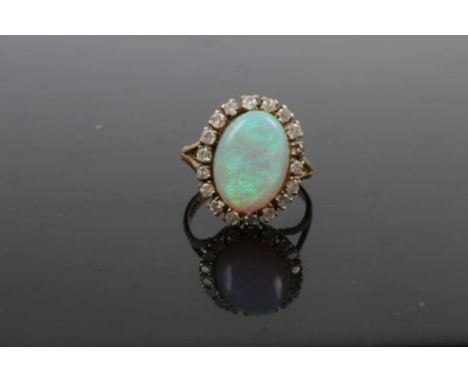 Opal and diamond cluster ring with an oval cabochon opal measuring approximately 14mm x 10mm x 4.1mm, surrounded by a border 