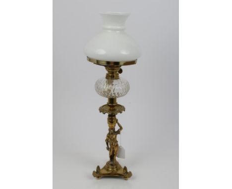 Decorative cast brass oil lamp, with funnel and opaline shade, above a brass section with flame adjuster, with a male figural