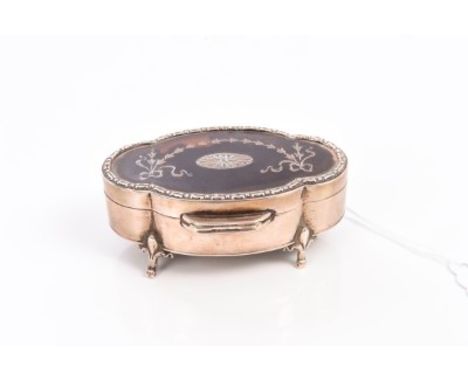 George V silver trinket box of shaped form, hinged silver mounted tortoiseshell cover with inset ribbon decoration, on four f