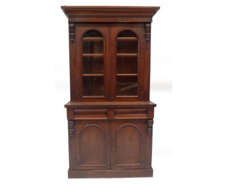 A Victorian mahogany cabinet bookcase, with ogee moulded cornice, over two arched glazed doors, revealing shelves, enclosed b