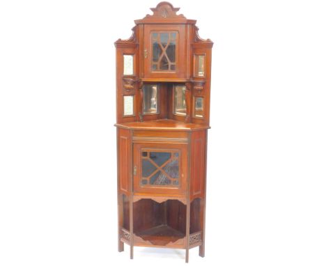 A late 19th/early 20thC walnut display cabinet, the top with a shaped crest above a glazed door, surrounded by bevelled mirro