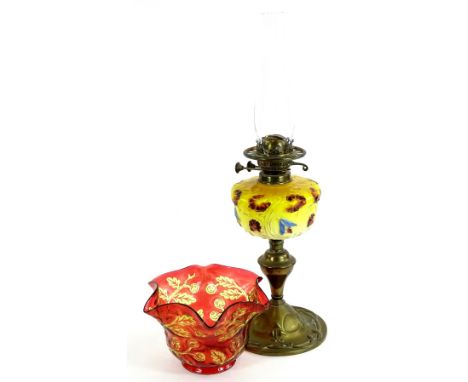 A Victorian brass oil lamp, the associated ruby tinted shade decorated with flowers and leaves, above an orange glass reservo