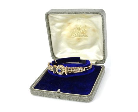 An Edwardian hinged bangle, set with central cluster of sapphire surrounded by seed pearls, with fine ball and wire design, a