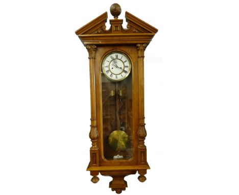 A late 19th/early 20thC Vienna wall clock, the break front crest with a central turned finial above a white enamel dial with 