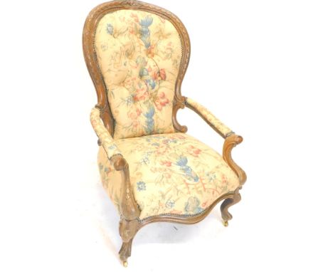 A Victorian walnut open armchair, the leaf carved show frame upholstered in pattern fabric with a button back padded arm rest