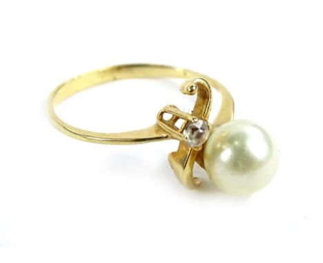 A modern dress ring, with single cultured pearl and white stone, in twist design, yellow metal, unmarked, ring size L, 1.8g a