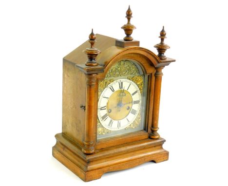 A late 19thC German mantel clock, in a walnut case, the arched dial applied with gilt metal embossed spandrels etc., the case