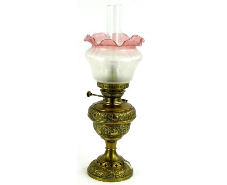 An early 20thC brass oil lamp, with clear funnel, frosted pink glass and shade, inverted stem and pierced domed foot, 56cm H.
