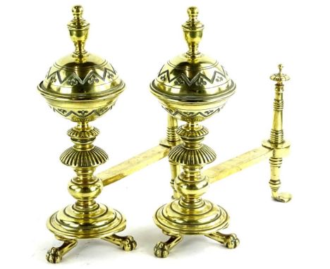 A pair of late 19thC aesthetic style fire dogs, each with a bulbous turned and engraved finial, circular stepped base and paw