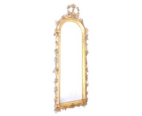 A Victorian gilt gesso wall mirror, the arch frame decorated with leaves and berries etc., 161cm H, 62cm W.Provenance: The pr