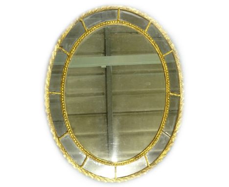 An oval gilt wall mirror, with central plate, surrounded by smaller plates, within beaded and gadrooned borders, 61cm x 75cm.