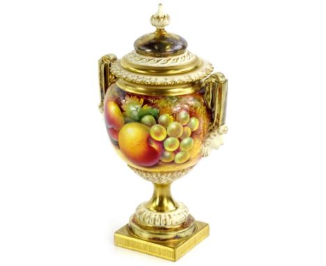 A Royal Worcester porcelain two handled urn and cover, painted with fruit by Paul English, the lid with a tapering finial, th