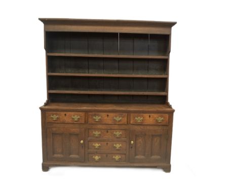 An 18thC oak dresser with plate rack, having moulded cornice, boarded back and three channelled shelves to the top, the base 