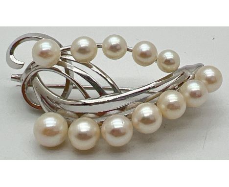 A silver and pearl floral design vintage brooch. Set with 12 graduating size white pearls. Marked Sterling to back. Approx. 4