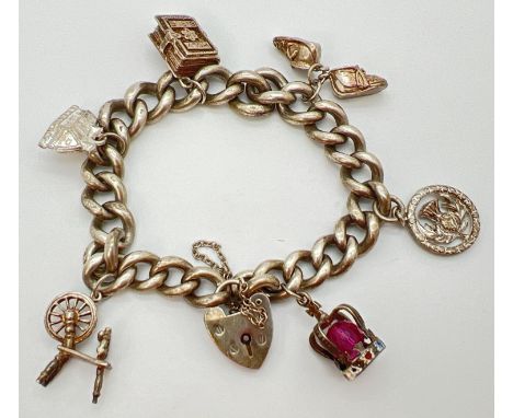 A vintage 1970's heavy silver curb chain charm bracelet with 6 charms. Heart shaped padlock clasp hallmarked for London 1974 