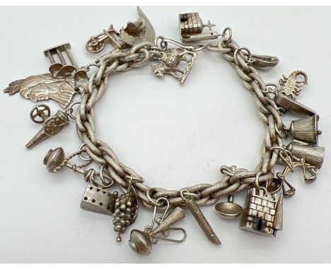 A vintage white metal charm bracelet with a quantity of assorted silver &amp; white metal charms. Triple link chain with 20 c