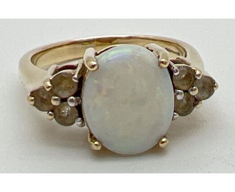 A 9ct yellow gold Ethiopian opal set dress ring. Large oval cabochon (approx. 11mm x 9mm) set between a cluster of 3 pale yel