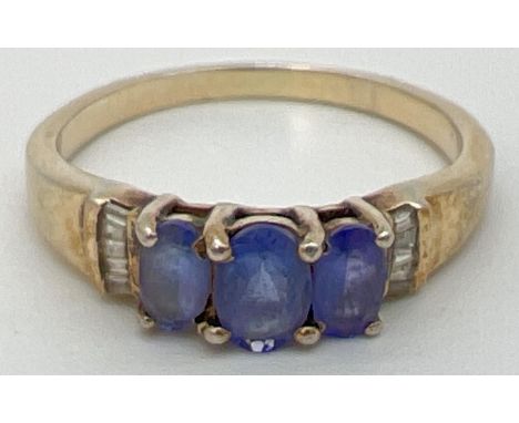 A silver gilt dress ring set with tanzanite's & 5 baguette cut diamonds to each shoulder. Stamped 925 inside band. Ring size 