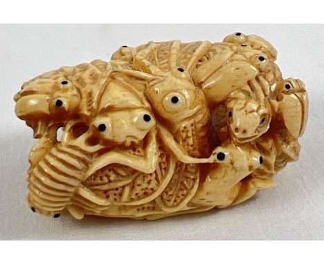 A carved bone netsuke in the form of a ring of crickets, beetles and bugs. Signature mark to reverse. Approx. 5cm long. 