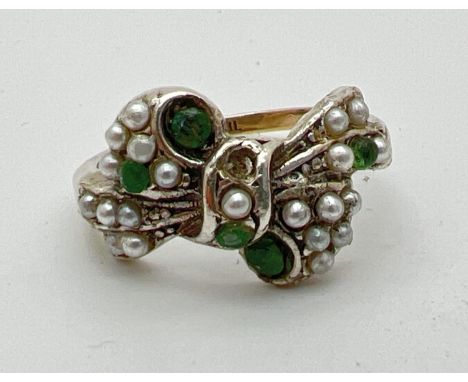 A vintage 9ct gold and silver bow design ring set with small cut emeralds and white faux pearls (two stones missing). Size LÂ